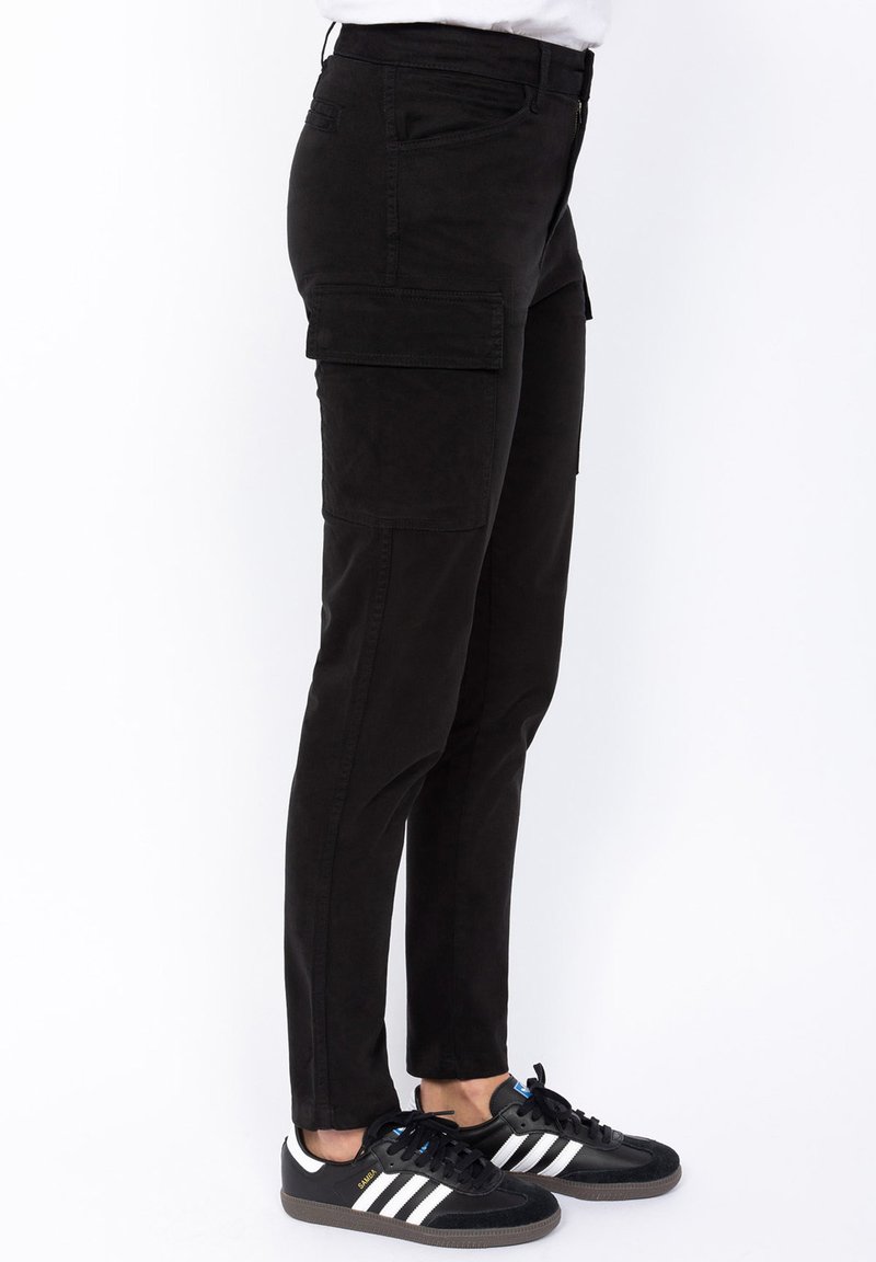 Zwarte cargobroek met zijzakken, slim fit, gemaakt van een katoenmix. Gecombineerd met zwarte sneakers met witte strepen.
