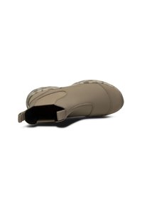 Scarpa slip-on color beige con tomaia sintetica liscia, design curvo e suola in gomma texturizzata. Presenta un pull tab per facilitare l'indossamento.