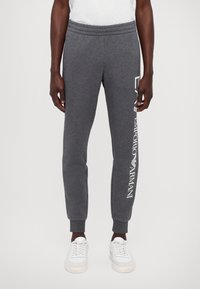 Szare spodnie dresowe wykonane z bawełnianej mieszanki, o dopasowanym kroju, z elastycznym pasem i białym nadrukiem logo na lewej nogawce.