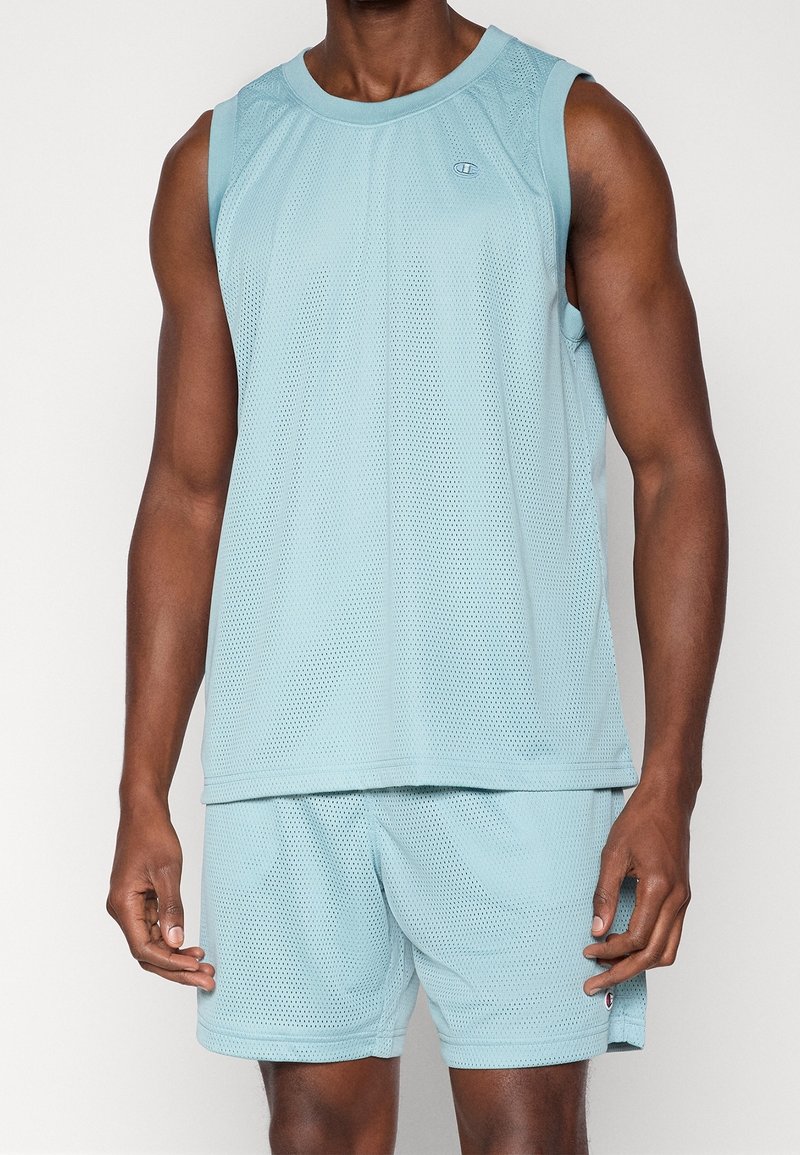 Homme portant un haut de sport sans manches en maille bleu clair et un short en maille assorti sur un fond uni.