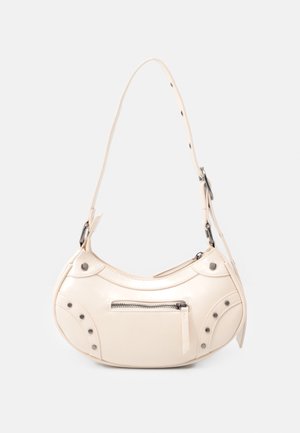 Petit sac à main crème de forme incurvée, poche avant zippée, clous métalliques décoratifs et sangle d'épaule réglable avec trous pour boucle.