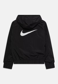 Sort Nike-jakke med hætte, elastiske manchetter og et hvidt swoosh-logo på ryggen. Glat tekstur med en tætsiddende pasform.