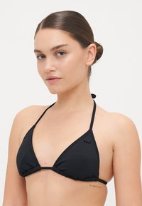 Black triangular bikini top with thin adjustable straps, gathered fabric along the edges, and a small logo detail on the left side.