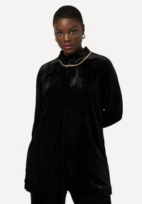 Vestito camicia in velluto nero con collo a camicia e maniche lunghe. Caratterizzato da una chiusura frontale, tessuto testurizzato e collana in catena dorata.