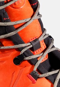Helle orange Wildleder-Wanderschuhe mit schwarzen Stoffakzenten. Ausgestattet mit grauen Schnürsenkeln, Texturdetails und einem sicheren Schnürverschluss.