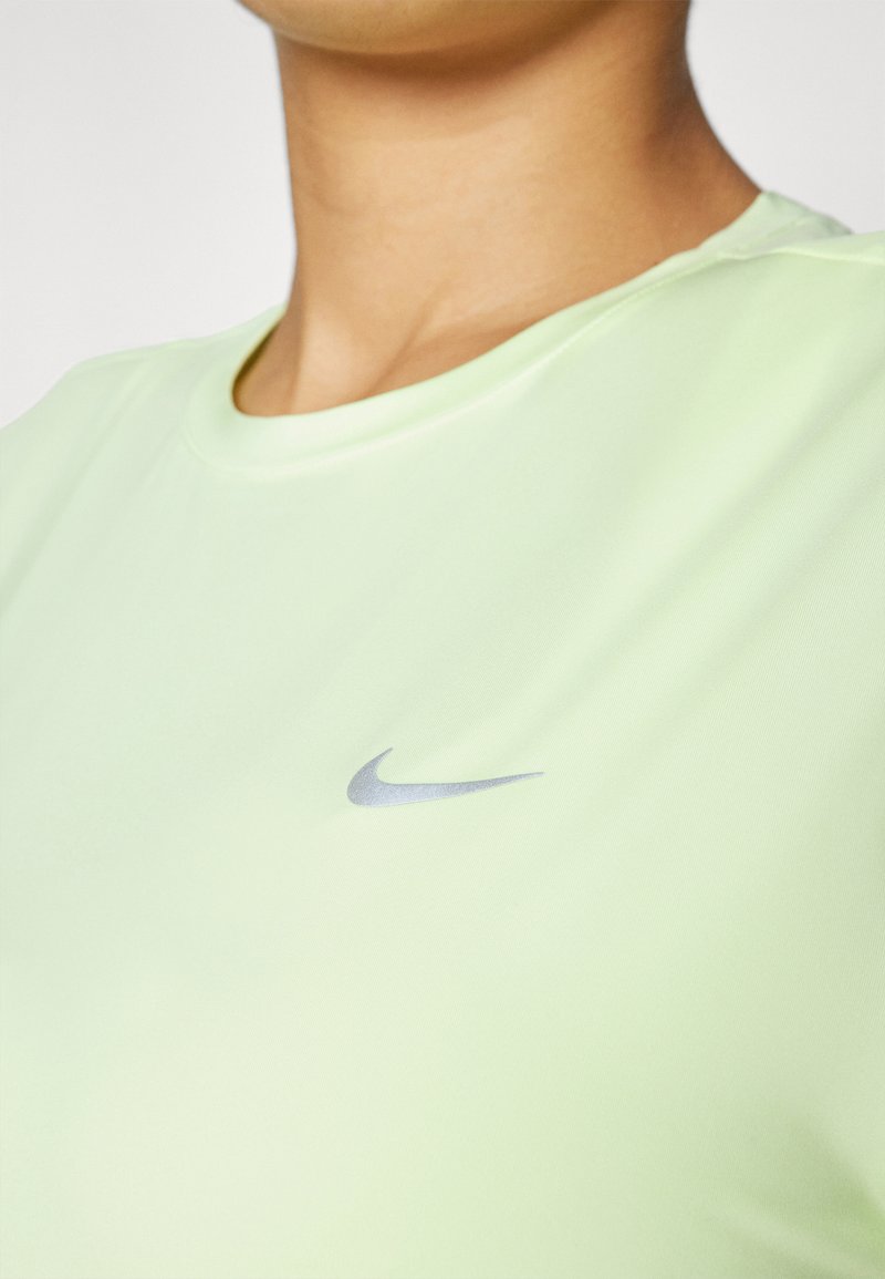 Helles grünes Sport-T-Shirt mit einem runden Halsausschnitt und kurzen Ärmeln, das ein silbernes Nike-Logo auf der linken Seite trägt. Glattes, leichtes Material.