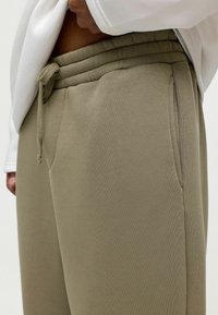 Relaxed-fit olijfgroene sweatpants van een katoenmix, met een elastische tailleband met trekkoord en zijzakken. Gladde textuur.