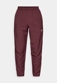 Vīrišķīgas bordo Nike sporta bikses ar elastīgu jostasvietu, pieguļošām bikšu kājām un sudraba logo. Izgatavotas no viegla auduma, ar gludu tekstūru un bez rakstiem.