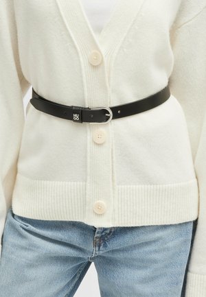 Ceinture en cuir noir avec boucle en argent, arborant le logo "Hugo", portée sur un cardigan crème à boutons avec une finition en tricot texturé.