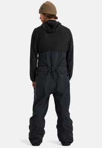 Czarowy, wodoodporny kombinezon z teksturowanym górnym częścią w odcieniach czerni i szarości, z dopasowanym pasem, regulowanymi ramiączkami oraz bocznymi kieszeniami na zamek.