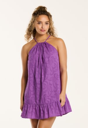 Violetti olkaimeton mekko, jossa on halterneck, teksturoitu kangas ja drapoinnilla varustettu pääntie. Mekossa on liehuva hame, jossa on rypytetty helma.