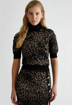 Top a maglia in stampa animale marrone e nera con collo alto, maniche corte a palloncino e orlo a coste, abbinato a una gonna coordinata con motivo e bottoni laterali.