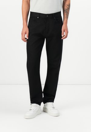 Black denim trousers with a straight cut, featuring a button closure, belt loops, and front and back pockets, worn with white sneakers.