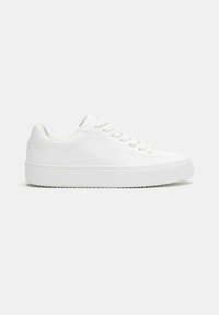 Sneakers bianchi in tela con profilo basso, punta rotonda e suola piatta in gomma. Le caratteristiche includono chiusura con lacci e design minimalista.
