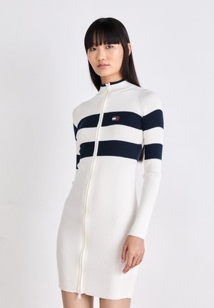 Abito in maglia a coste bianco con righe orizzontali blu navy, chiusura frontale con zip a tutta lunghezza, maniche lunghe e piccolo logo sul petto.
