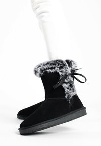 Stivaletti neri in suede con risvolto in pelliccia sintetica, dettagli in pizzo e suola in gomma nera, caratterizzati da una texture liscia e punta arrotondata.
