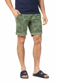 Green camo shorts with rolled cuffs, featuring side pockets and a relaxed fit. Worn with navy slip-on sandals and a navy shirt.