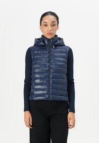 Navy padded vest with a high collar and zip closure. Features horizontal quilted pattern and is made from a glossy material.