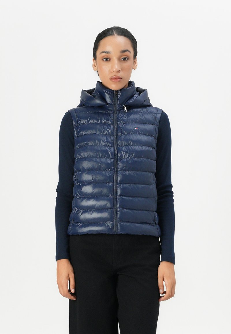 Navy padded vest with a high collar and zip closure. Features horizontal quilted pattern and is made from a glossy material.