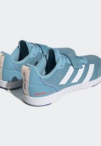 Baskets bleu clair avec des rayures blanches, en matériau texturé, col rembourré et onglet de talon contrastant. Présente un détail imprimé rouge sur le côté.