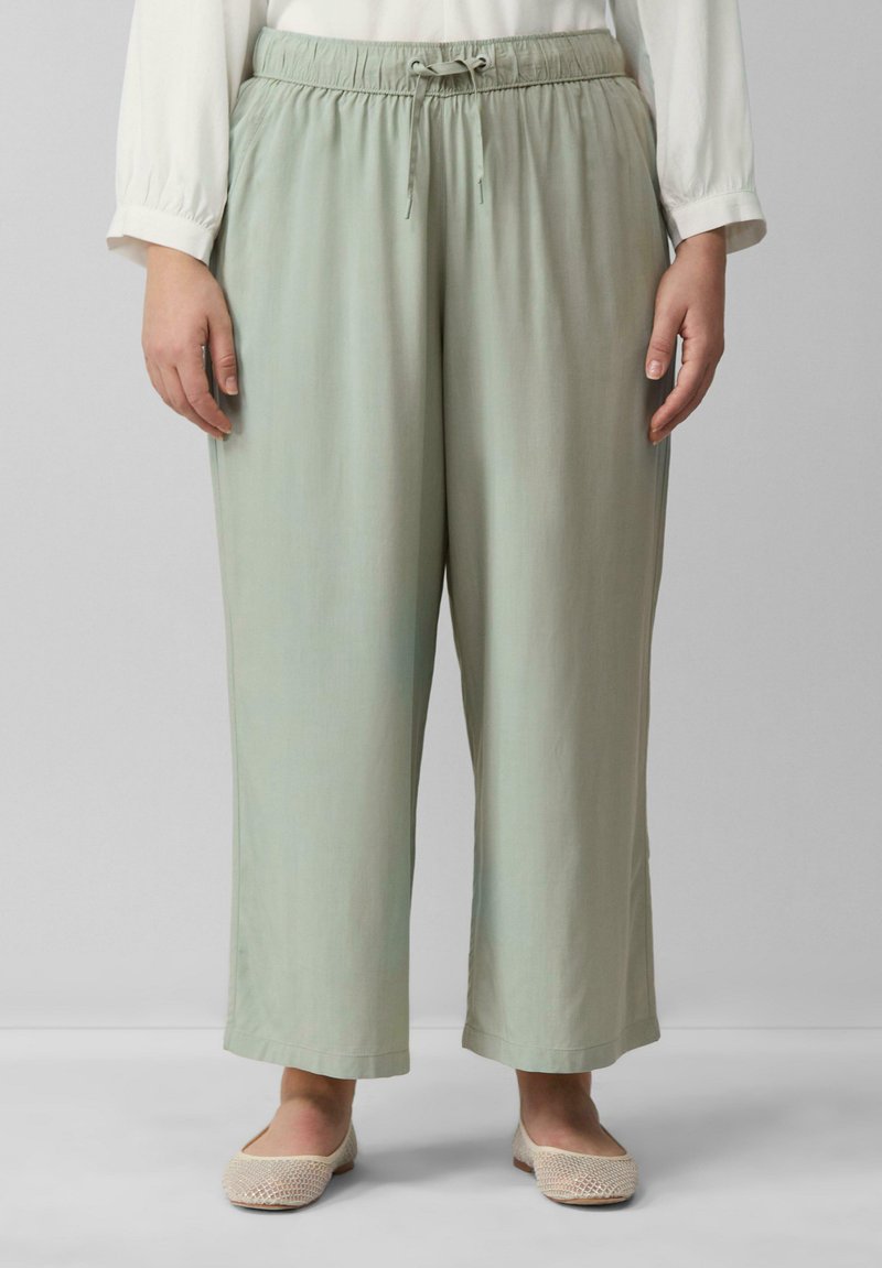 Pantalons légers en vert doux, décontractés, avec une taille élastique et un cordon de serrage, fabriqués en tissu doux. Un devant plat et des jambes larges complètent le design.