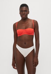 Crvena bikini gornji dio s žicom i podesivim trakama, uparena s bijelim donjim dijelom visokog struka koji ima mali detalj mašne sprijeda.