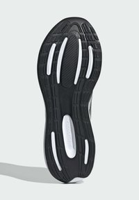 Čierna gumová podrážka tenisky s textúrovaným povrchom, s bielymi akcentmi a drážkami pre trakciu, označená "CLOUDFOAM."