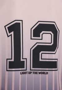 Sort tallet 12 med hvid kant på et lyserødt stribet stof, teksten "LIGHT UP THE WORLD" under tallet.