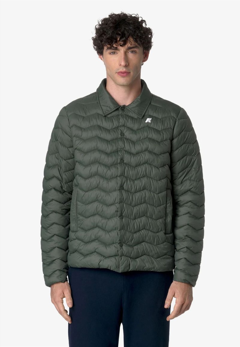 Giacca imbottita verde con chiusura a bottoni, colletto a punta e cuciture orizzontali. Presenta un piccolo logo sul lato sinistro del petto.