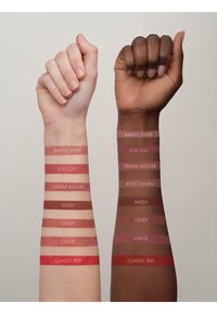 Campioni di colori per labbra su due braccia; una chiara, una scura. Le tonalità includono: Barely There, Lou Lou, Dream Bigger, Missy, Cindy, Chloe, Classic Red.