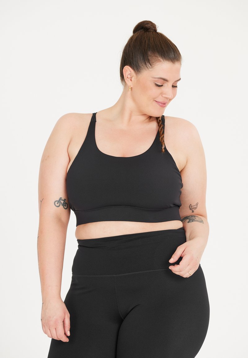 Zwarte sportbeha met brede straps en een ondersteunende band, gecombineerd met bijpassende zwarte high-waisted leggings. Gladde, rekbare stof.