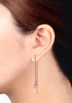 Pendientes de oro rosa con una larga cadena y un colgante circular con strass transparentes incrustados, colgando elegantemente del lóbulo de la oreja.