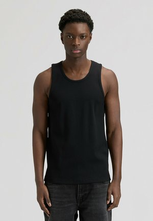 Sort ærmeløs tanktop med ribbet tekstur, rund halsudskæring og afslappet pasform. Kombineret med mørk denim-jeans.