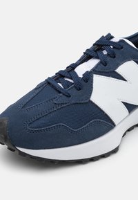 Marineblaue Sneaker mit Obermaterial aus Mesh und Wildleder, weißen Akzenten, strukturierter Außensohle und traditionellem Schnürdesign.