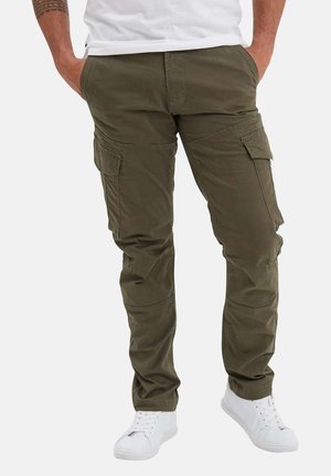 Pantalons cargo vert olive avec plusieurs poches latérales, coupe fuselée et tissu durable. Portés avec des baskets blanches et un t-shirt blanc.