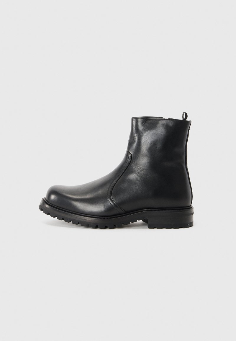 Boots de glezna din piele neagră, cu o textură netedă, vârf rotund și talpă rugged. Prezintă o bandă de tragere la spate și un design minimalist.