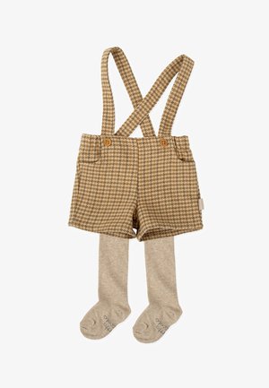 Peto corto marrón de houndstooth con tirantes cruzados, con botones de madera y combinado con medias de punto beige. Textura suave en todo su recorrido.