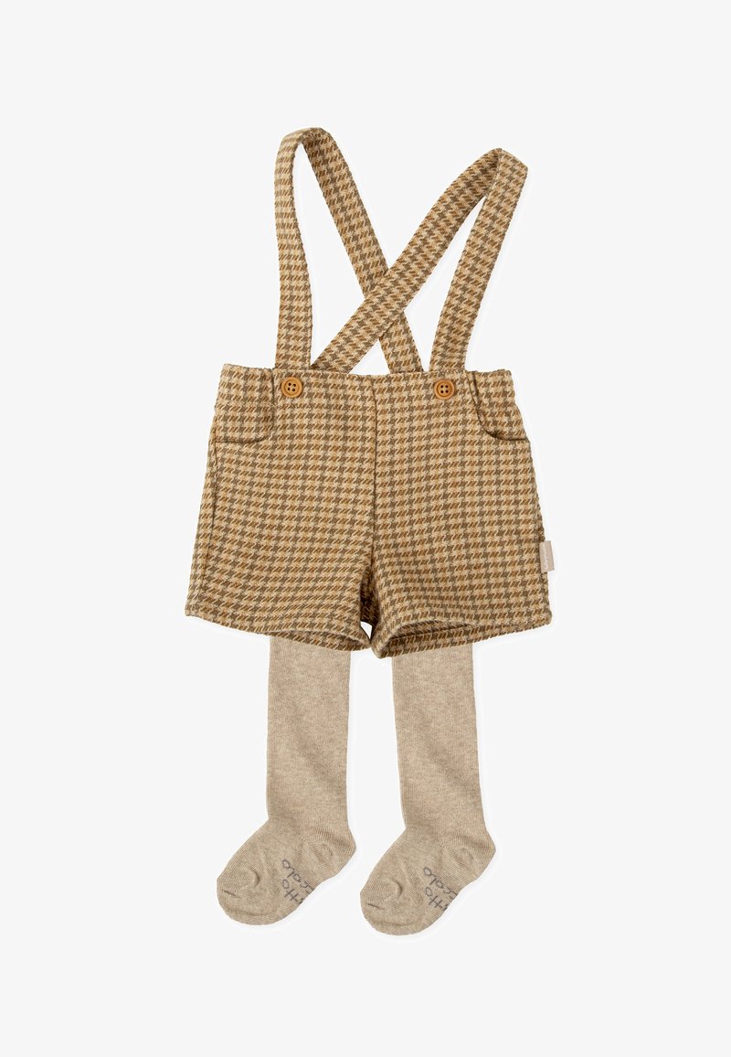 Peto corto marrón de houndstooth con tirantes cruzados, con botones de madera y combinado con medias de punto beige. Textura suave en todo su recorrido.