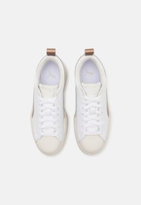 Weiße Sneaker mit einem glatten Lederobermaterial, beigem Gummisohle, runder Zehenpartie und passenden Schnürsenkeln. Metallische Akzente an der Ferse.