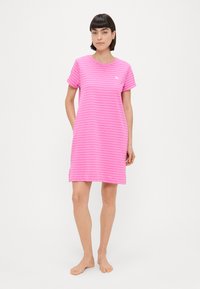 Rožinė dryžuota miego suknelė su trumpomis rankovėmis, apvalia kaklo iškirpte ir šoninėmis kišenėmis. Pagaminta iš švelnaus audinio; turi logotipą ant krūtinės.