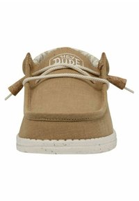 Zapato slip-on de lienzo beige con punta redondeada, cordones elásticos y detalle de corcho texturizado en el talón. Suela de goma blanca con manchas.