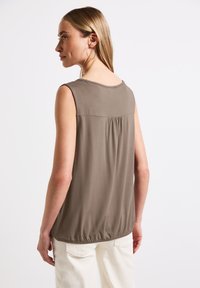 Top senza maniche in tessuto verde oliva, presenta un design con raccolto sul retro e orlo elasticizzato, con una trama morbida e scollatura arrotondata.