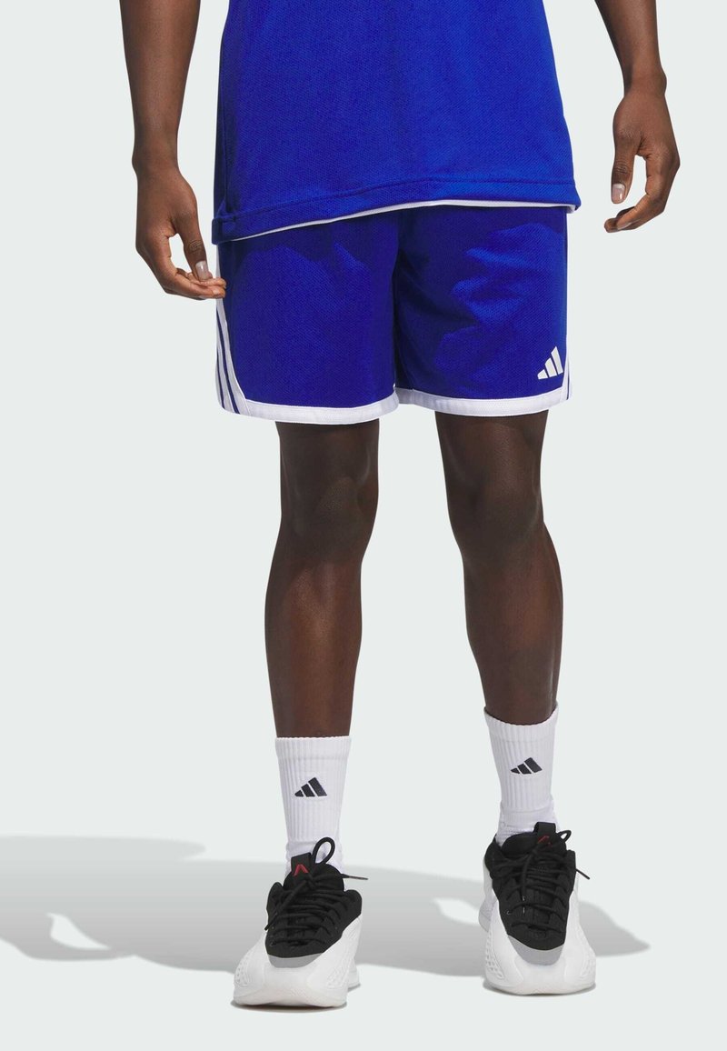 Blaue Sportshorts mit weißen Akzenten, die drei Streifen an den Seiten und ein Adidas-Logo aufweisen. Getragen mit schwarzen Schuhen und weißen Socken.