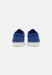 Blue suede sneakers with a white rubber sole, rounded back, and mesh lining. Features standard lacing and cushioned ankle support.