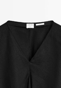 Černý lněný top s designem ve tvaru V a decentním skladem ve středu zad. Štítek nese nápis "Massimo Dutti Studio."