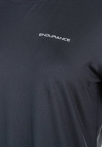Mustapohjaista urheilupaitaa, joka on valmistettu sileästä ja kevyestä kankaasta. Paidan etupuolella on pyöreä kaula-aukko ja valkoinen "ENDURANCE"-logo.