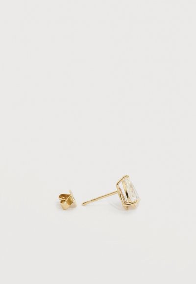 Χρυσό σκουλαρίκι με διαφανή πολύτιμη πέτρα σε σχήμα σταγόνας και ξεχωριστό χρυσό κλιπ πεταλούδα σε άσπρη επιφάνεια.