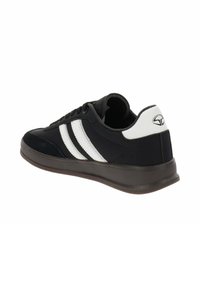 Zapatilla deportiva negra con franjas blancas, material sintético suave, suela plana marrón, collar acolchado, puntera redondeada y un logotipo en el talón.