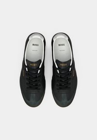 Adidași negri pentru sport, confecționați din materiale din suede și țesătură, cu un design cu șireturi, vârful în contrast verde și branding-ul auriu "BOSS" pe laterale.