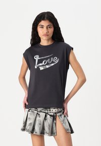 Fekete, ujjú nélküli póló fényes "Love" grafikával; szürke, redős szoknyával párosítva, amely denim hatású és oldalsó kivágott részlettel rendelkezik.